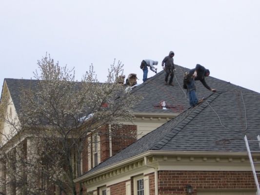 a group of men working on the roof of a house.